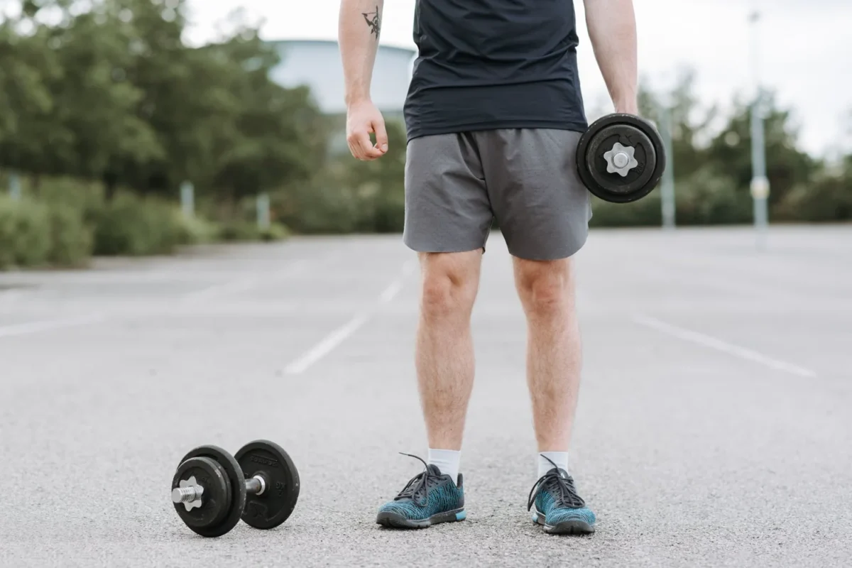 Man standing outdoors with dumbbells ready for a strength-training session