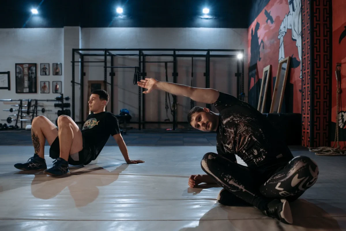 Two men stretching on the floor of a gym during a lighter recovery-focused session