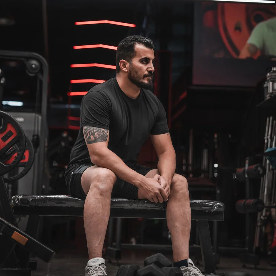 Gym member seated between sets beside dumbbells